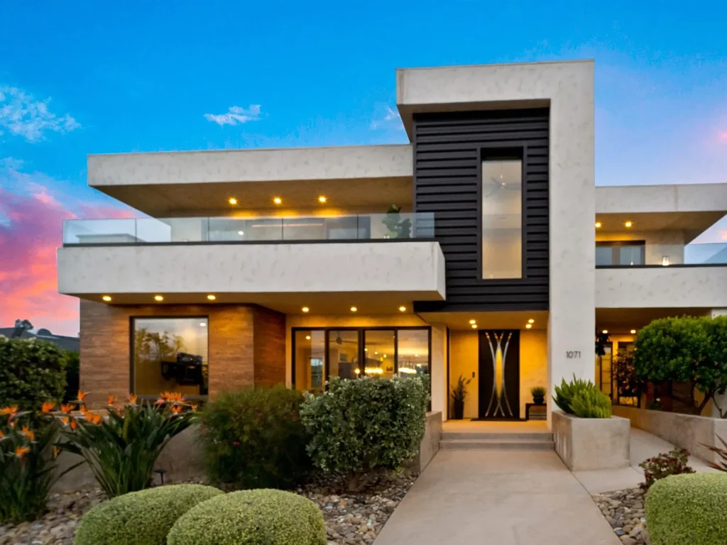 Two story house California real estate with big windows and green plants in front.