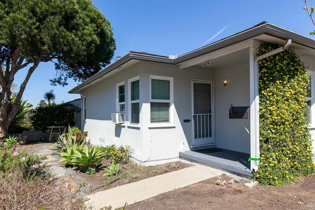 White house California real estate with small porch and green plants around.