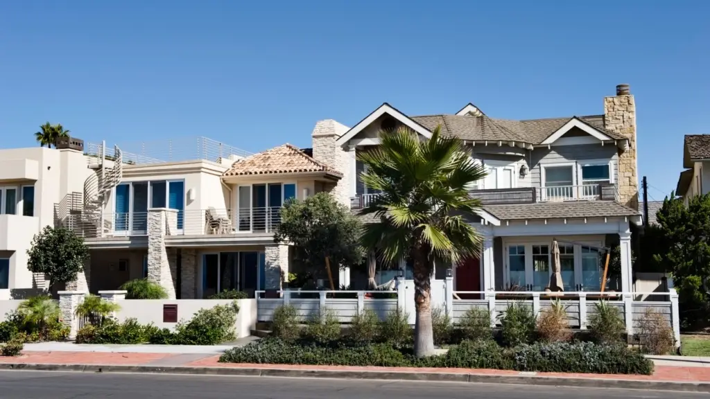 Two houses California real estate with palm trees and green plants in front.