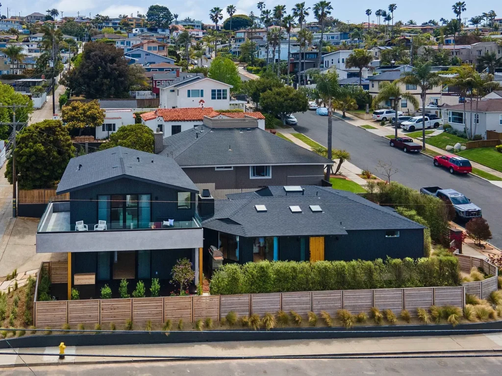 Aerial view of a house California real estate with green trees and other homes around.