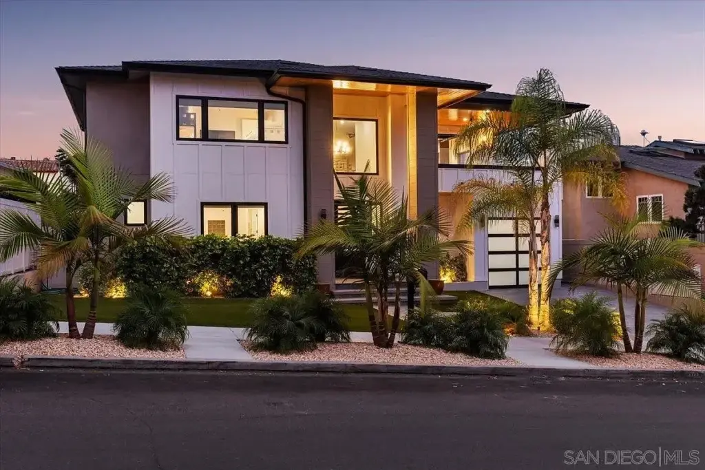 Two story house California real estate with big windows, palm trees, and a garden in front.