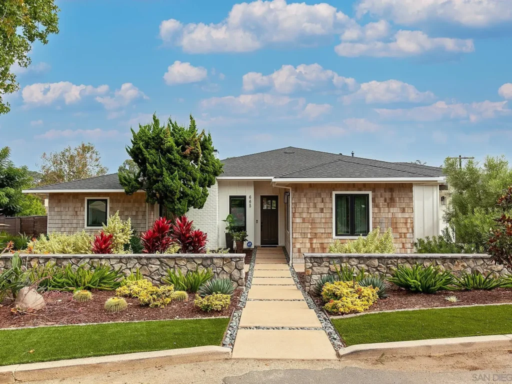 One story house California real estate with stone and wood walls and green plants by the path.