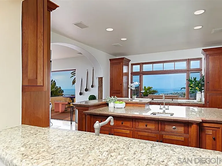 Mediterranean-style kitchen with wooden cabinetry and large windows at 1135 Barcelona Drive