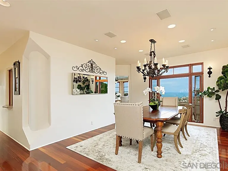 Bright Mediterranean-style dining area with decorative chandelier and large windows