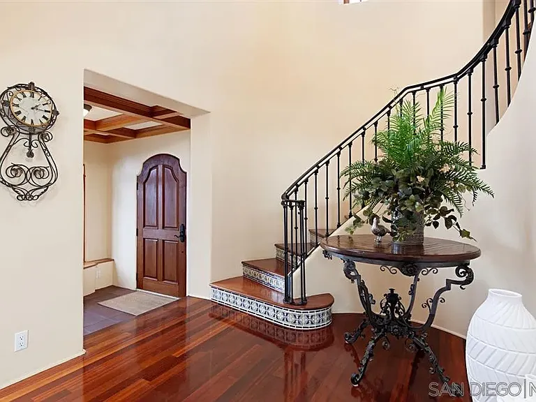 Mediterranean-style entryway with staircase, wooden doors, and indoor plants