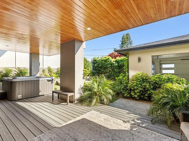 Covered outdoor patio with wood-paneled ceiling and landscaped surroundings