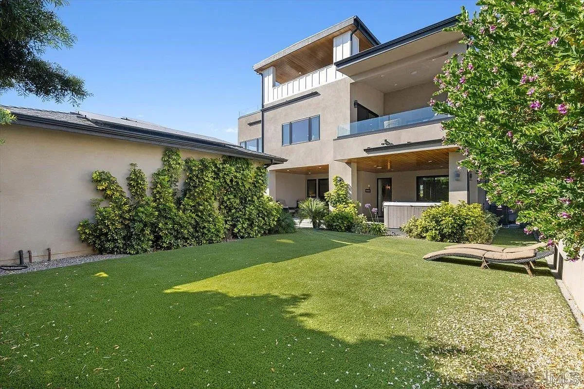 Rear exterior of modern home with balconies and spacious green lawn