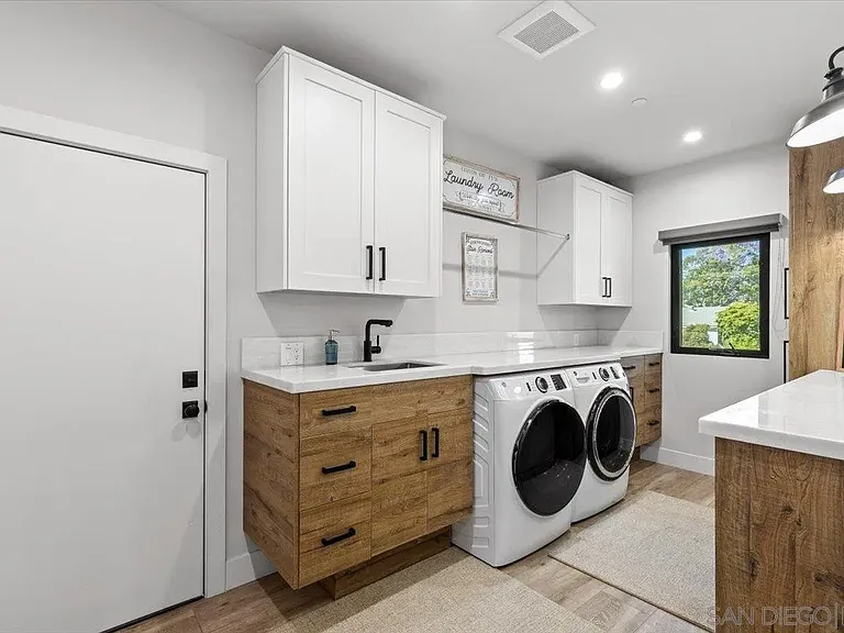 Modern laundry room with white cabinetry and washer and dryer at 4515 Tivoli Street
