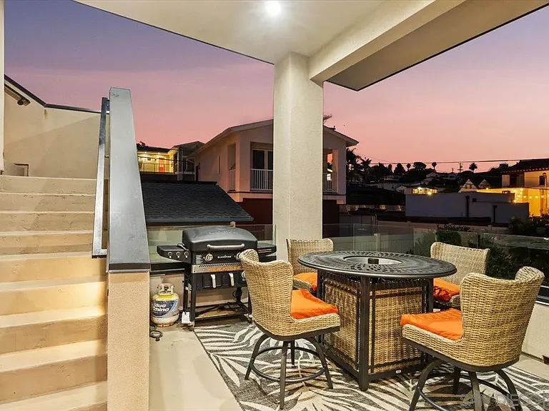 Rooftop dining area with built-in outdoor kitchen and evening views