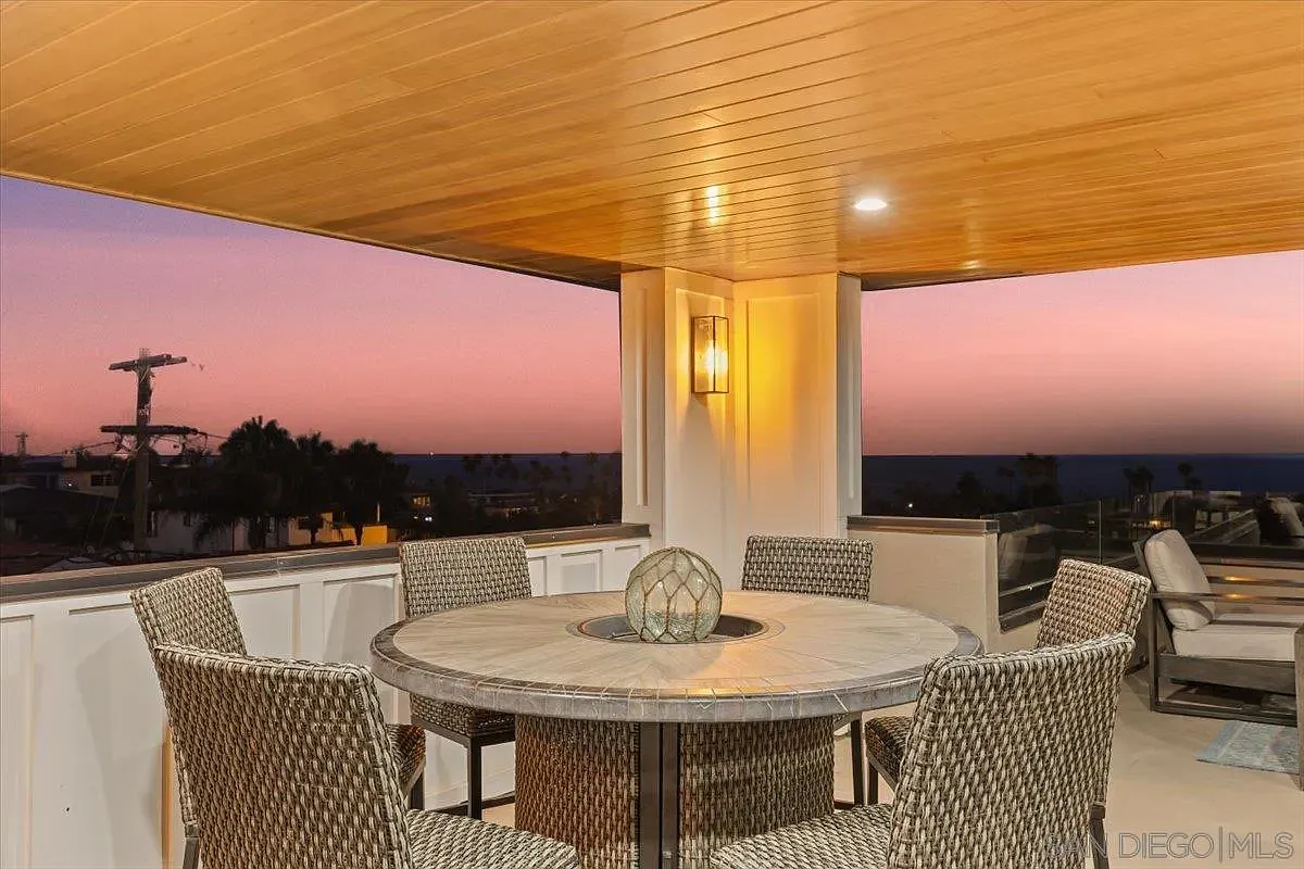 Covered rooftop entertainment area with outdoor kitchen and sunset views